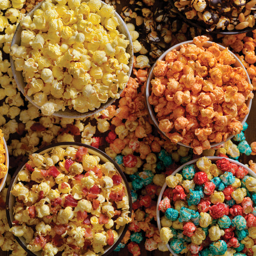 Assorted colorful popcorn in small bowls on a wooden surface